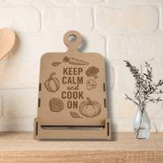 Engraved wooden stand styled with farmhouse accessories: wooden utensils in a tin can and a small vase with an olive branch.